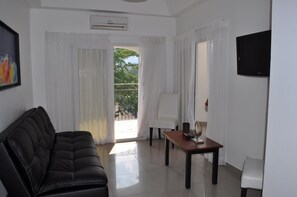 Relax in a stylish living area with a sofa, coffee table, and armchair, featuring a large window and flat-screen TV.