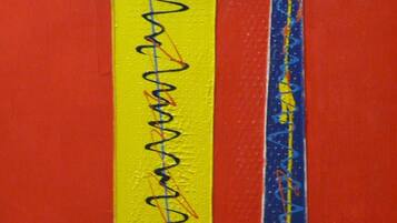 A close-up of a wall with two vertical stripes, one yellow and one blue, with scribbles on them.