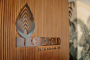A logo with a leaf design and the word 'eden' on a wooden panel.