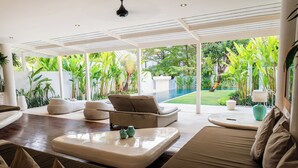 Un espai interior modern amb vista a una piscina, un sofà i zona de menjador.