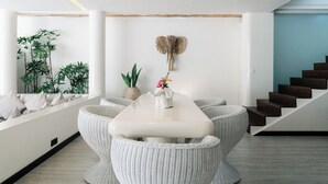 Un interior modern amb taula de dinar, cadires de vimet, una escultura d'elefant penjada a la paret i una escala.