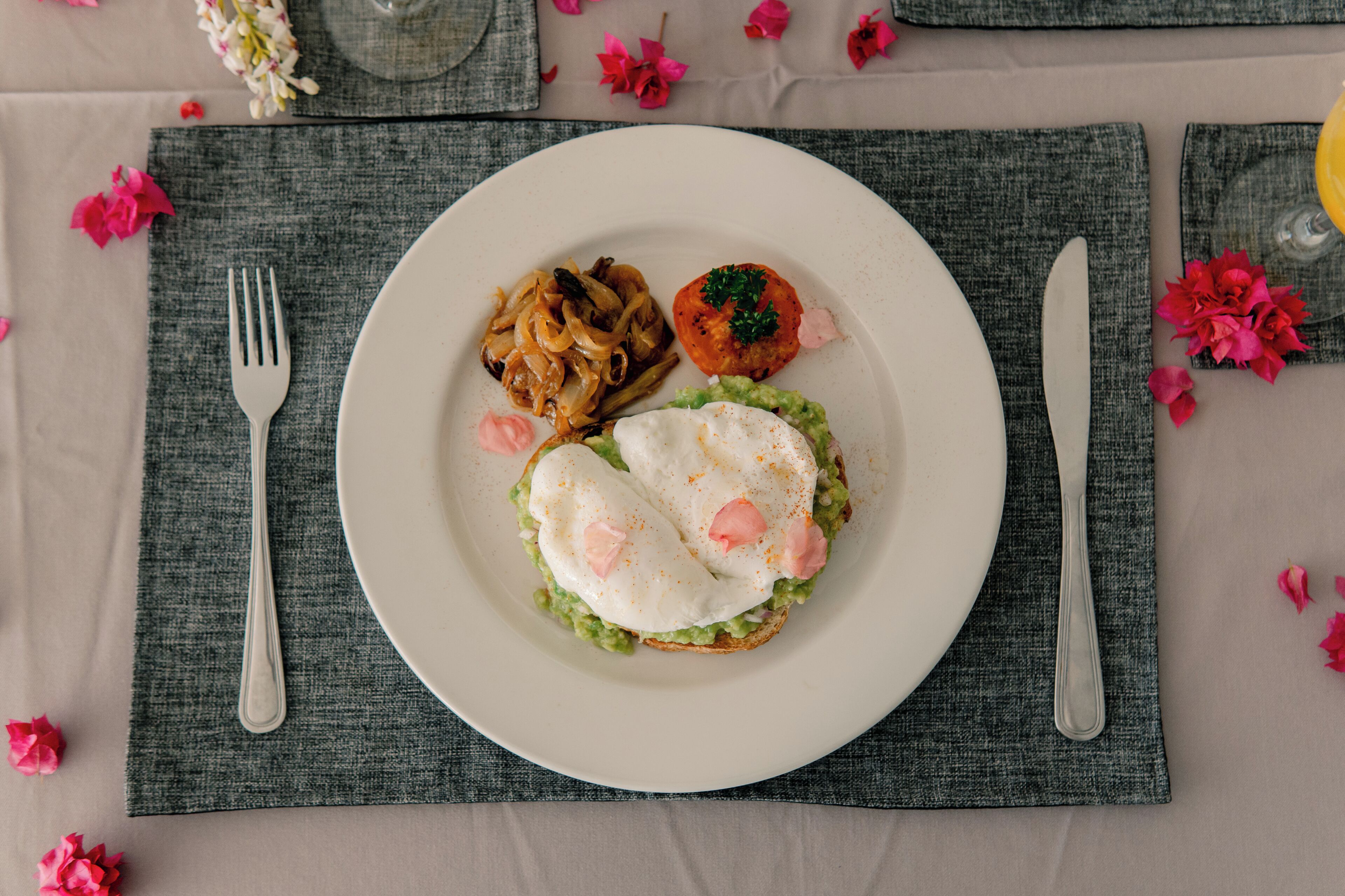 A plate with food, a fork, and a knife on a table with a placemat.