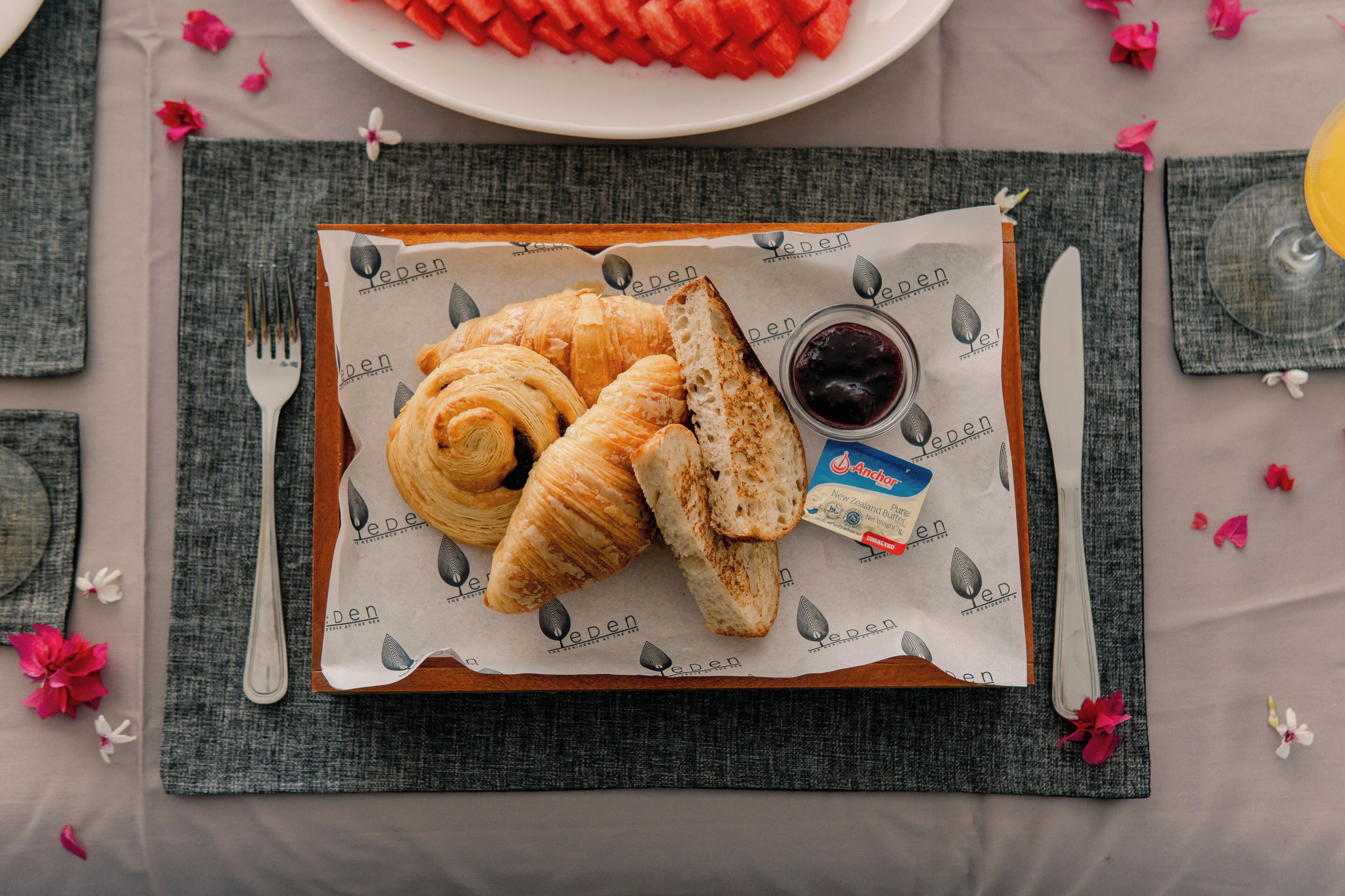 Una mesa servida con cruasanes, mermelada y una servilleta con un logotipo.
