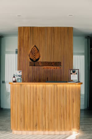 A reception desk with vertical wooden slats, a logo, and a website sign.