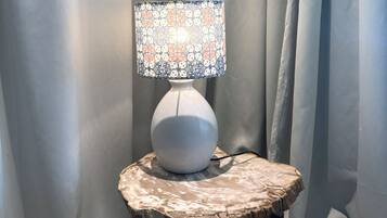 A white table lamp with a patterned lampshade on a rustic wooden table.