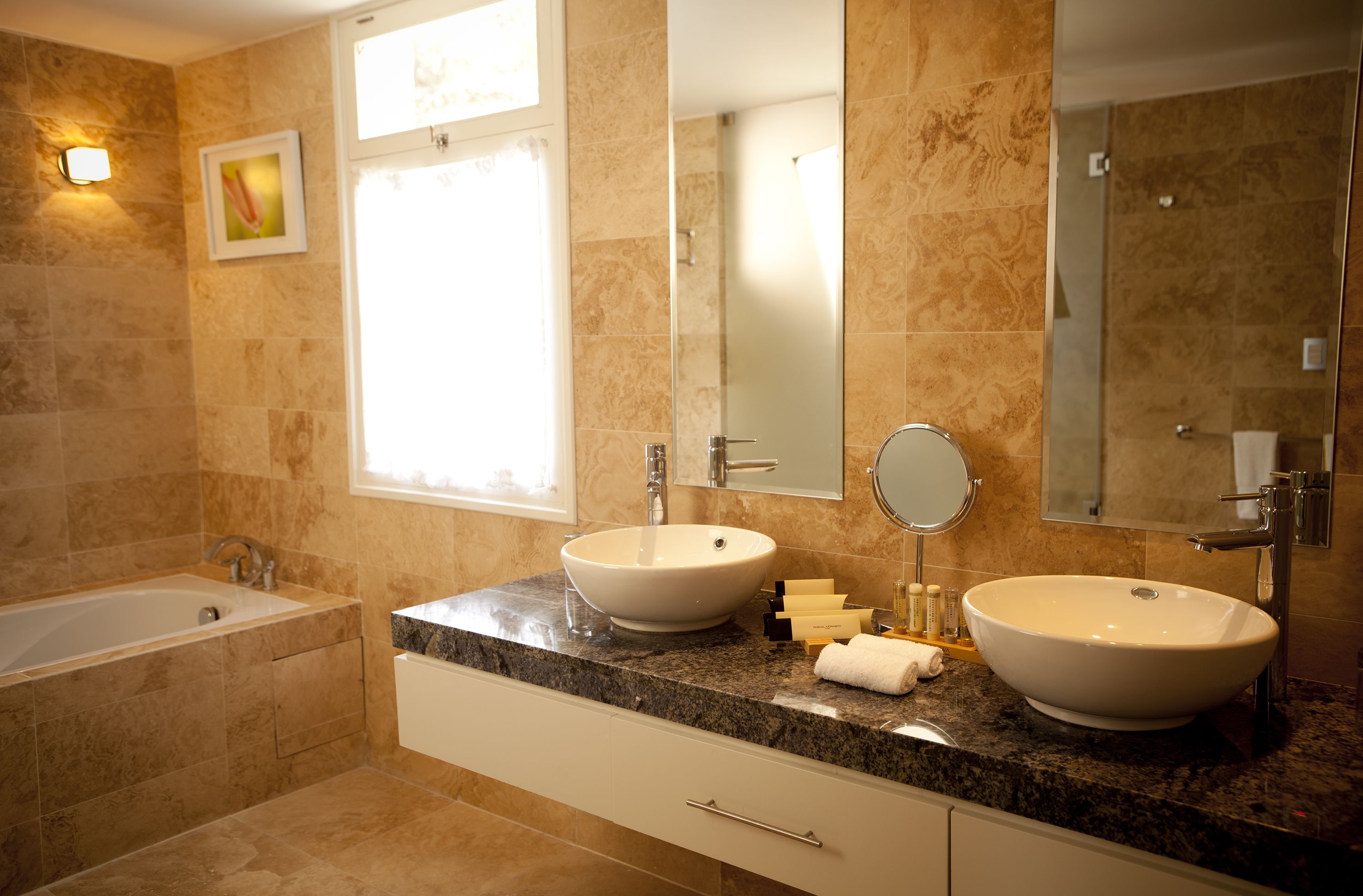 Une salle de bain avec deux lavabos, une baignoire et un grand miroir.
