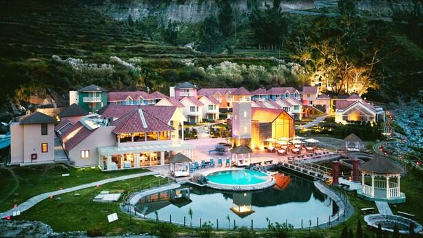 Un complexe hôtelier comprenant plusieurs bâtiments, une piscine et un paysage montagneux en toile de fond.
