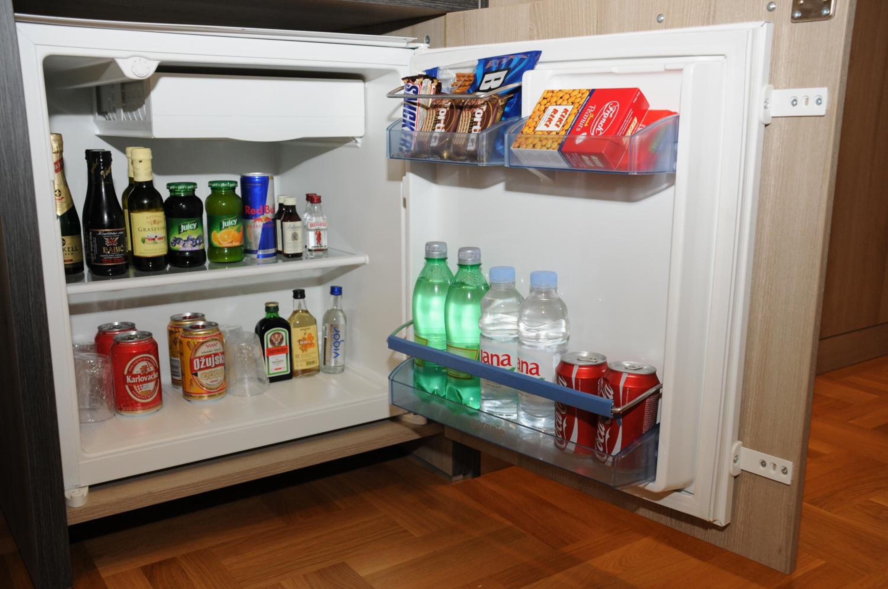 Un refrigerador abierto lleno de bebidas y aperitivos.