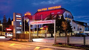 A hotel with a red roof and a sign for 'Calypso Restoran-Hotel'.
