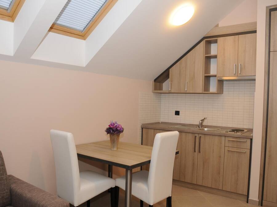 A modern kitchen with wooden cabinets, a white tiled backsplash, and a skylight above the dining area.