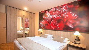 A hotel room with a large bed, two bedside tables with lamps, a wardrobe, and a large wall art piece.