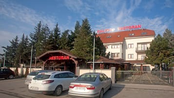 Un edificio con un letrero que dice "Restoran" y "Calypso" en el techo. Hay dos coches estacionados adelante.