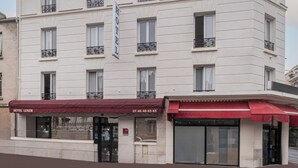 A multi-story hotel with a white facade, multiple balconies, and a red awning. - Hôtel Luxor (Issy-les-Moulineaux)
