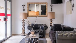 A modern living room with a leather sofa, a glass coffee table, and a mirror on the wall. - Hôtel Luxor (Issy-les-Moulineaux)