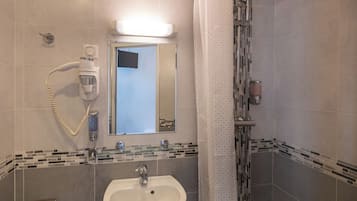 A bathroom with a sink, mirror, and shower.