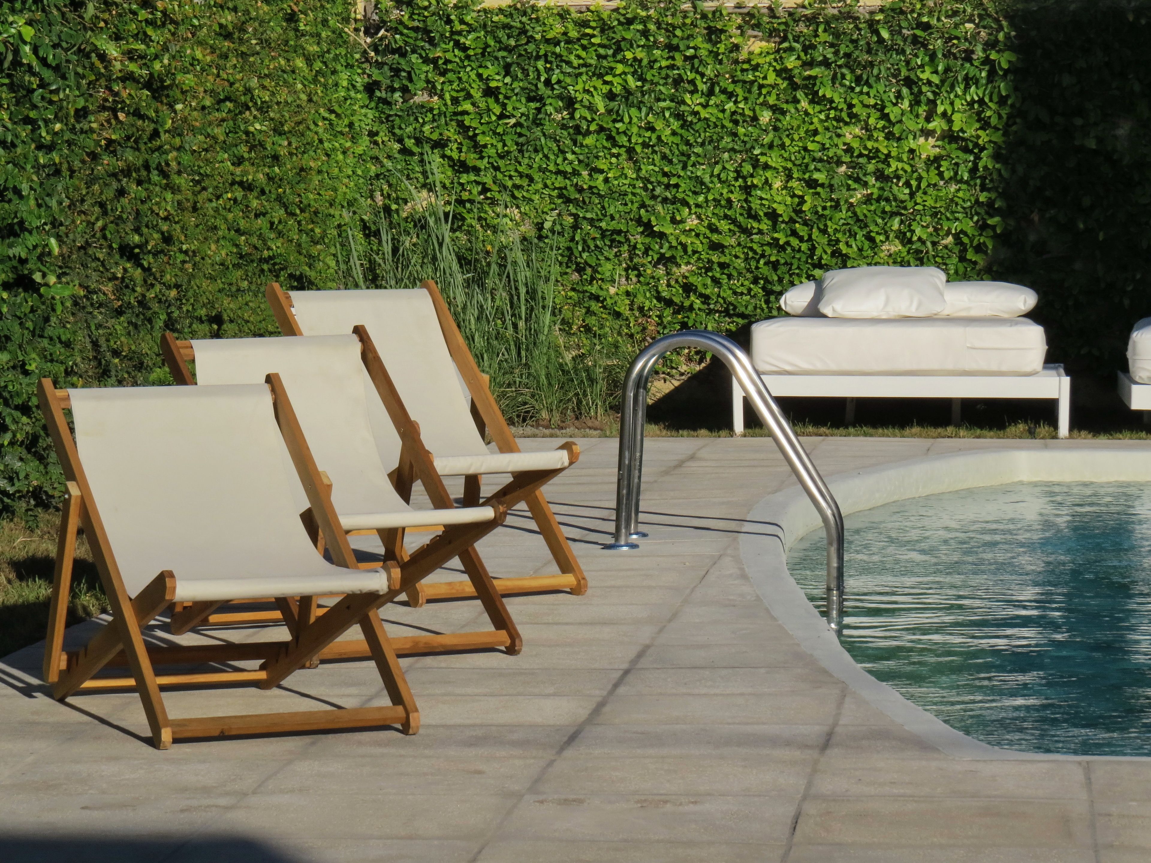 A poolside area with wooden lounge chairs and a white sofa.