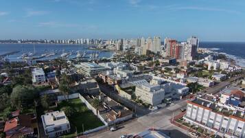 Un paisaje urbano costero con un puerto deportivo, edificios residenciales y un hotel moderno y alto.