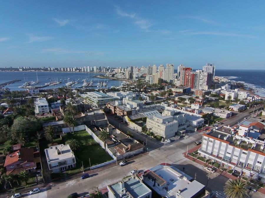 Un paisaje urbano costero con un puerto deportivo, edificios residenciales y un hotel moderno y alto.