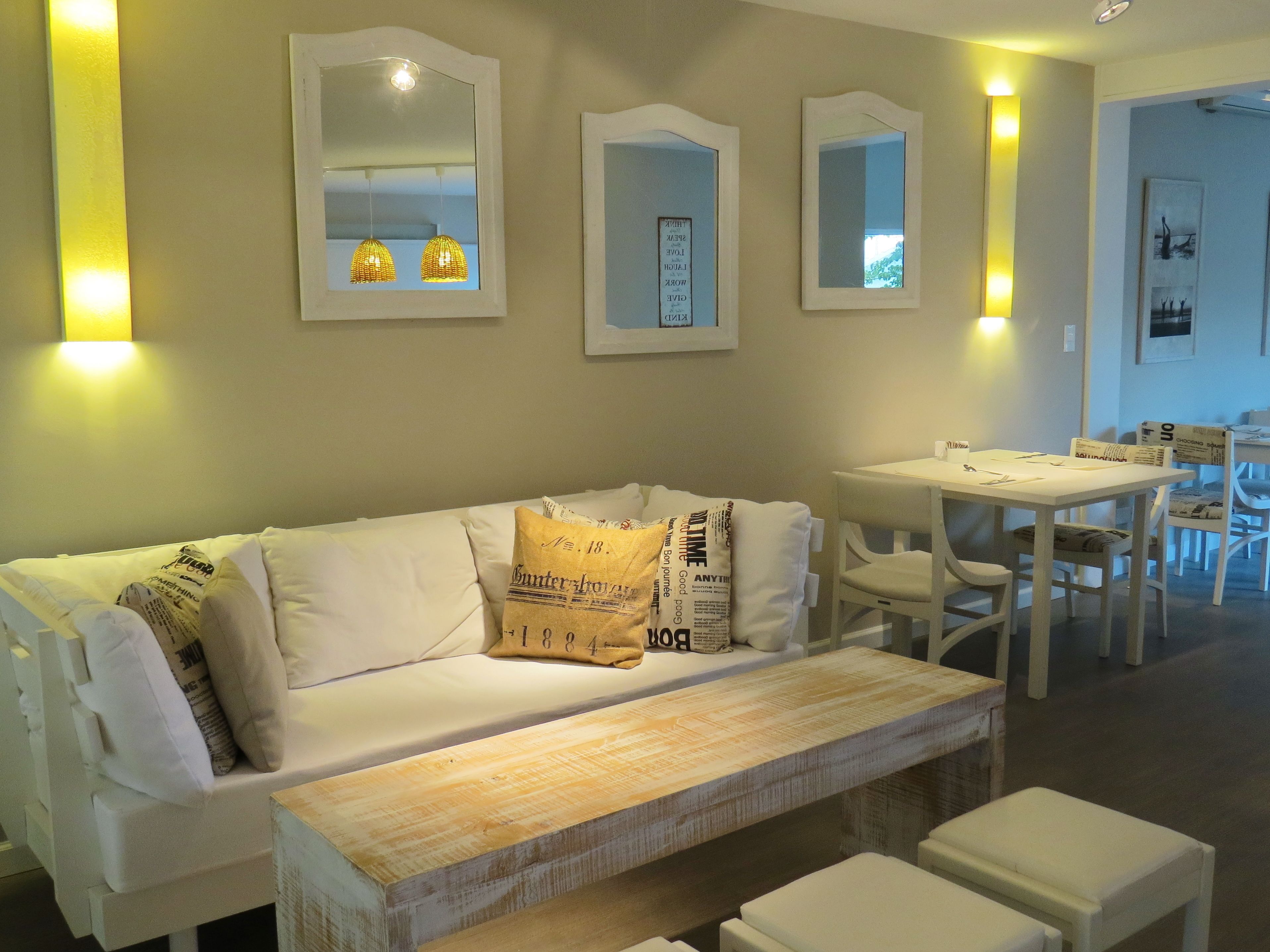 A modern living room with a white sofa, a wooden coffee table, and a dining area with a white table and chairs.
