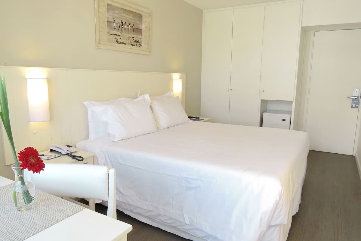 Une chambre d’hôtel avec un lit, une table de chevet, une lampe et un tableau encadré au mur.