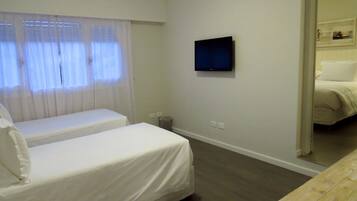 Ein Hotelzimmer mit zwei Einzelbetten, einem an der Wand montierten Fernseher und einer Klimaanlage.