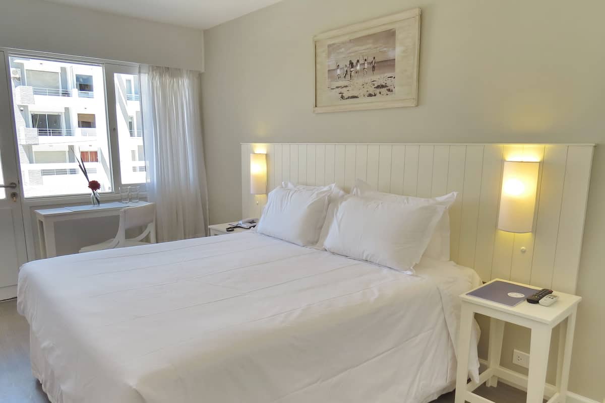 Une chambre d’hôtel avec un grand lit, un bureau et une chaise.