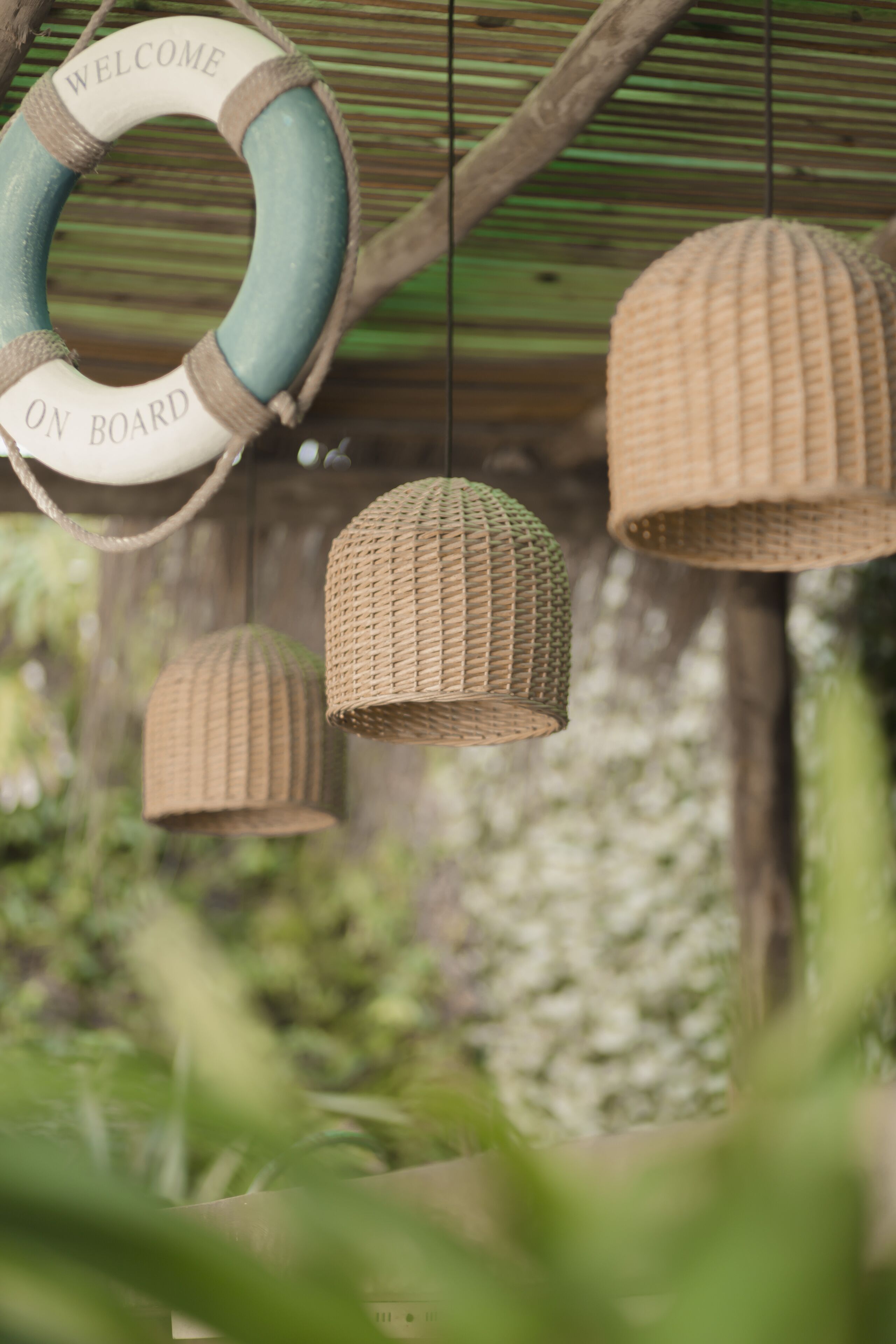 A lifebuoy with "WELCOME ON BOARD" text, and three wicker hanging lamps.