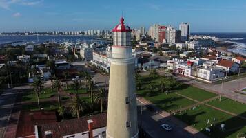 Un paisaje urbano costero con un faro destacado, edificios modernos y un puerto deportivo.