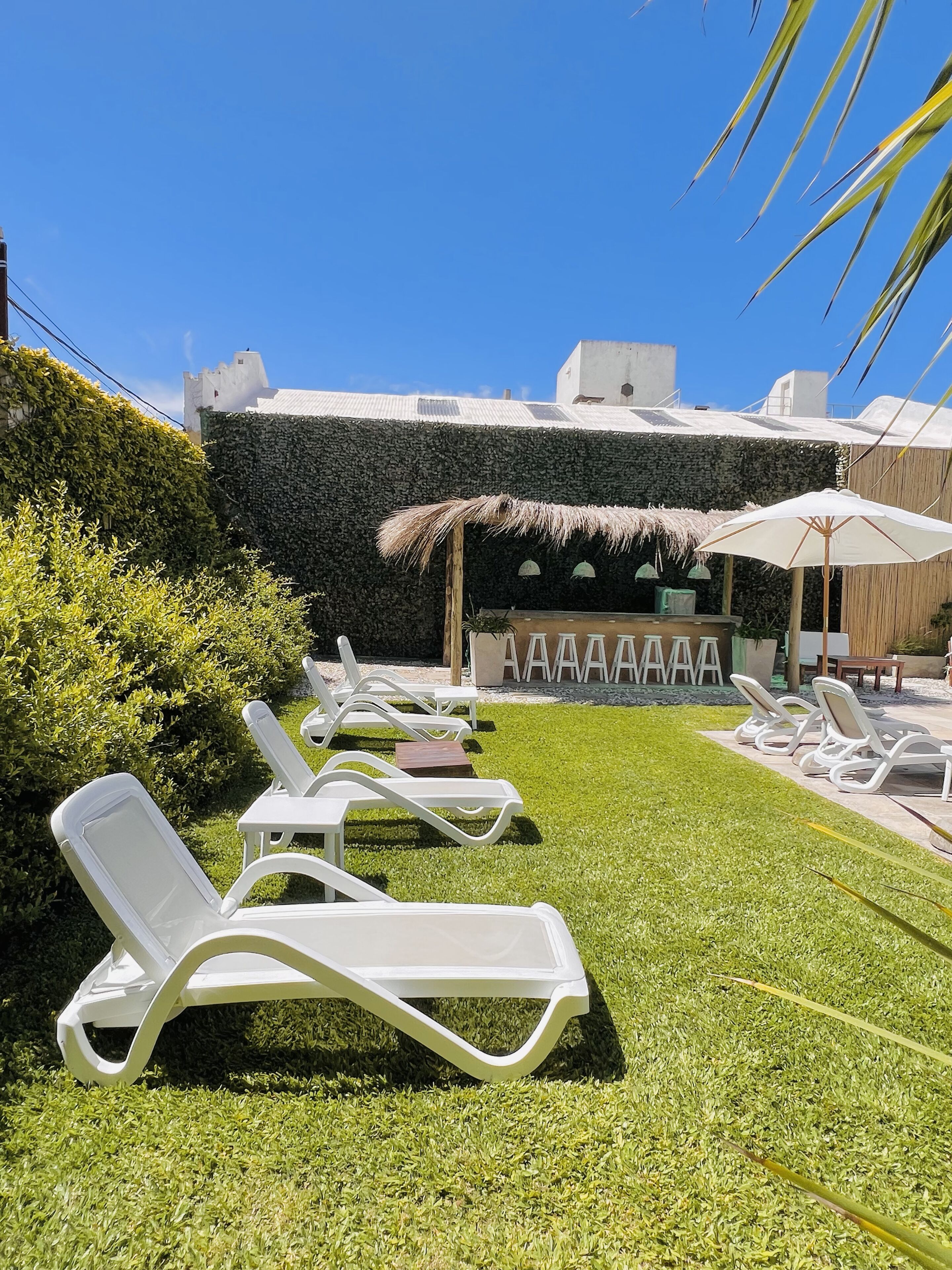 A poolside area with white lounge chairs and a thatched umbrella.