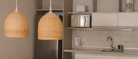 Una cocina moderna con encimera de madera, lámparas colgantes, horno empotrado y refrigerador de acero inoxidable.