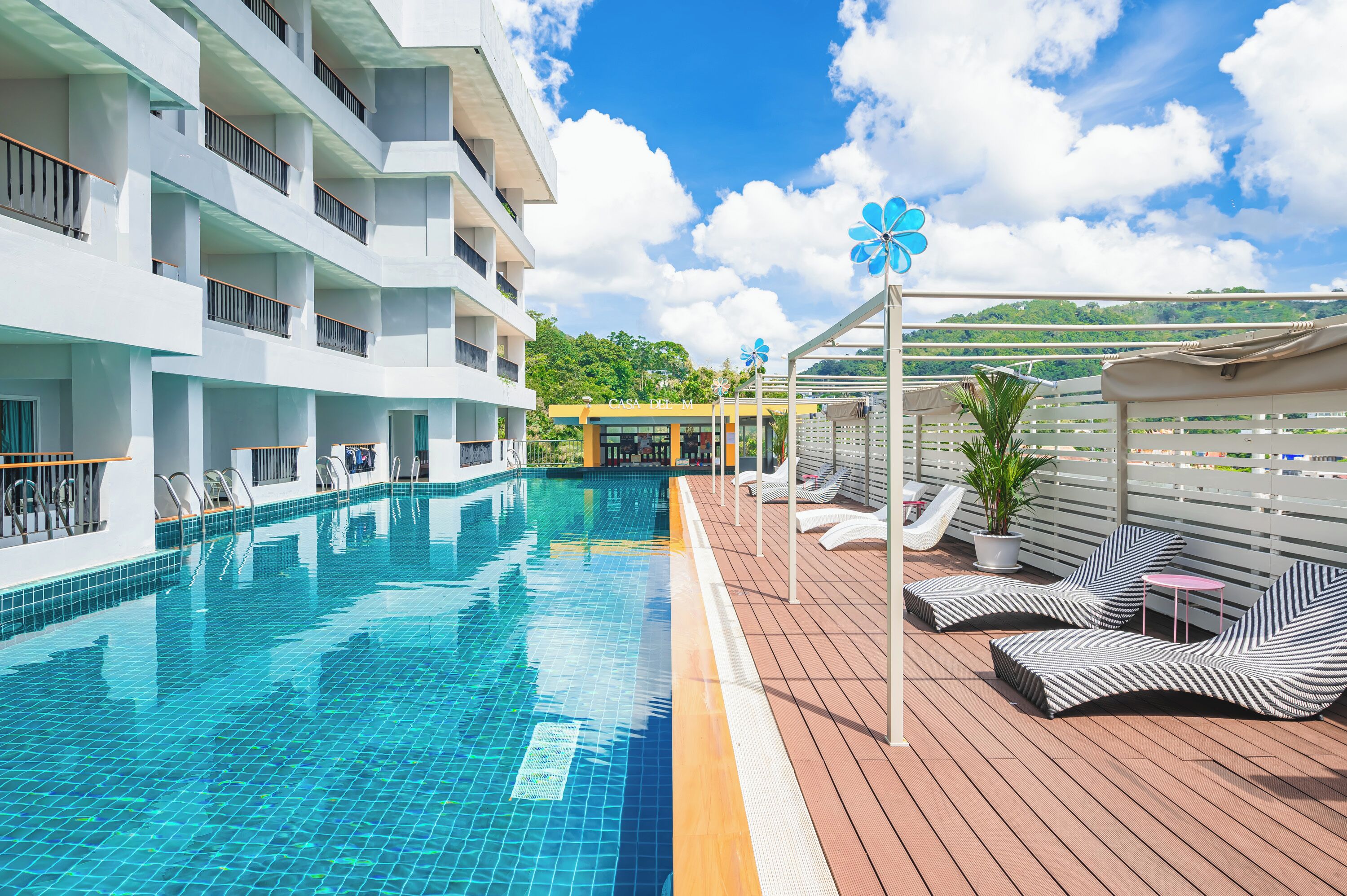 A swimming pool with lounge chairs and a building with balconies.