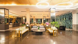 A spacious lobby with a modern design, featuring a reception desk, seating area with sofas and a coffee table, and a decorative wall with geometric patterns. - Casa Del M Phuket (Patong)