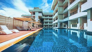 A swimming pool with tiled flooring, sun loungers, and a wooden deck. - Casa Del M Phuket (Patong)