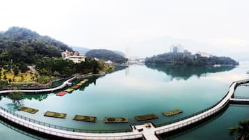 A circular water body with a walkway, surrounded by greenery and buildings.