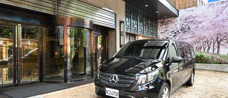 A black Mercedes-Benz SUV parked in front of a building with a stone facade and large glass doors.