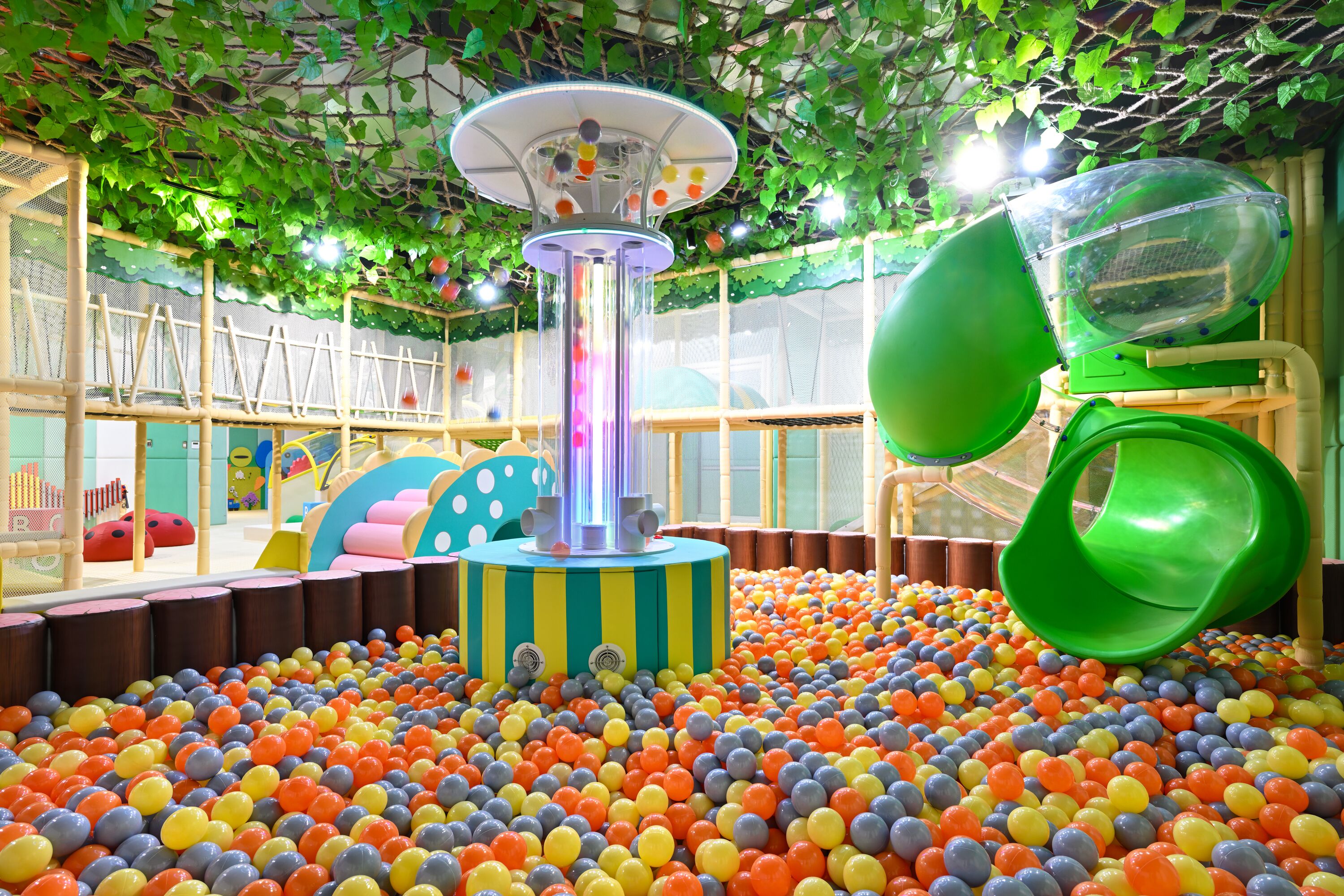 Zona de juegos con piscina de pelotas, tobogán y estructura para escalar.