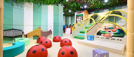 A children's play area with soft play structures, a slide, and a climbing net.