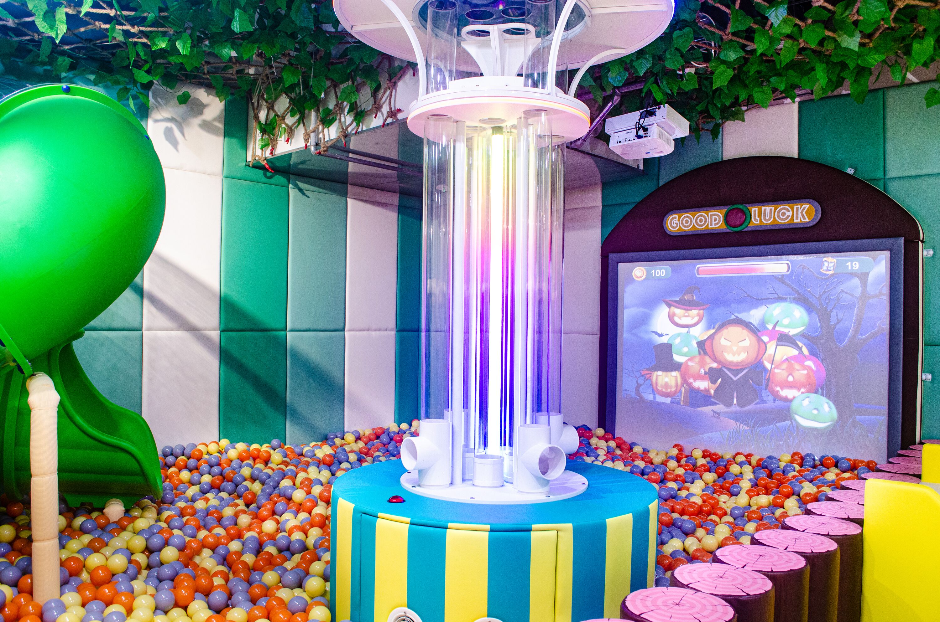 A colorful play area with a ball pit, a green slide, and a 'Good Luck' game machine.