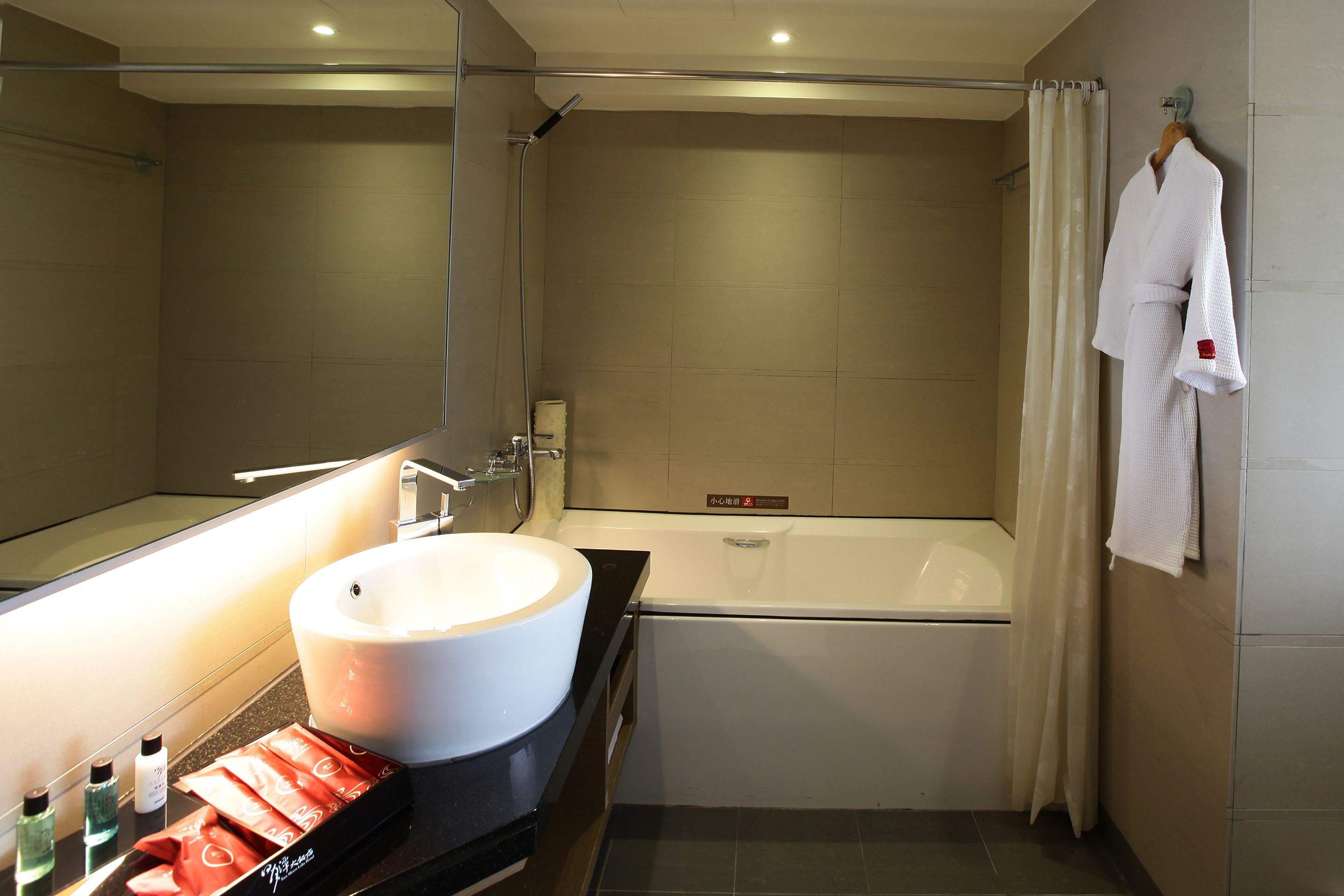 A modern bathroom with a large sink, a bathtub, and a mirror.