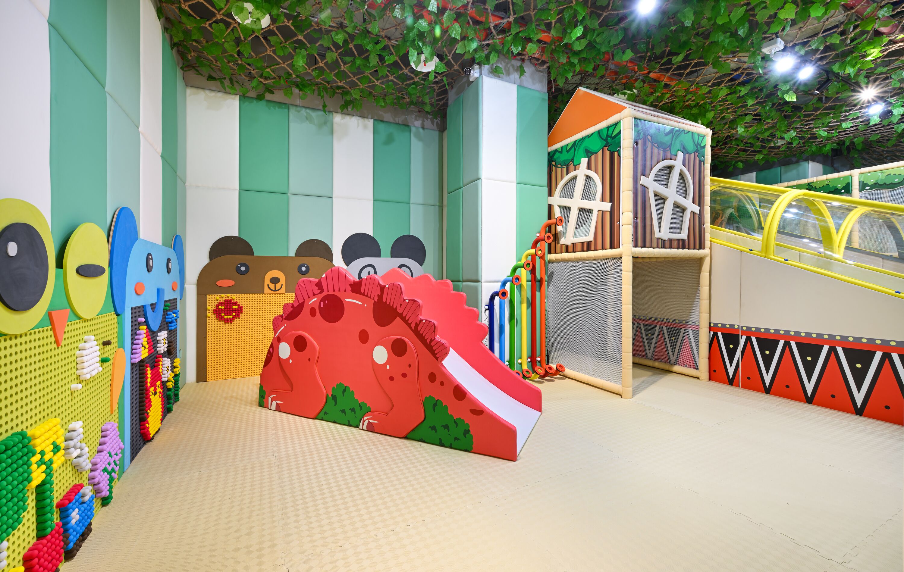 Ein Spielbereich mit bunten Spielgeräten, einer Rutsche und einer Kletterwand.