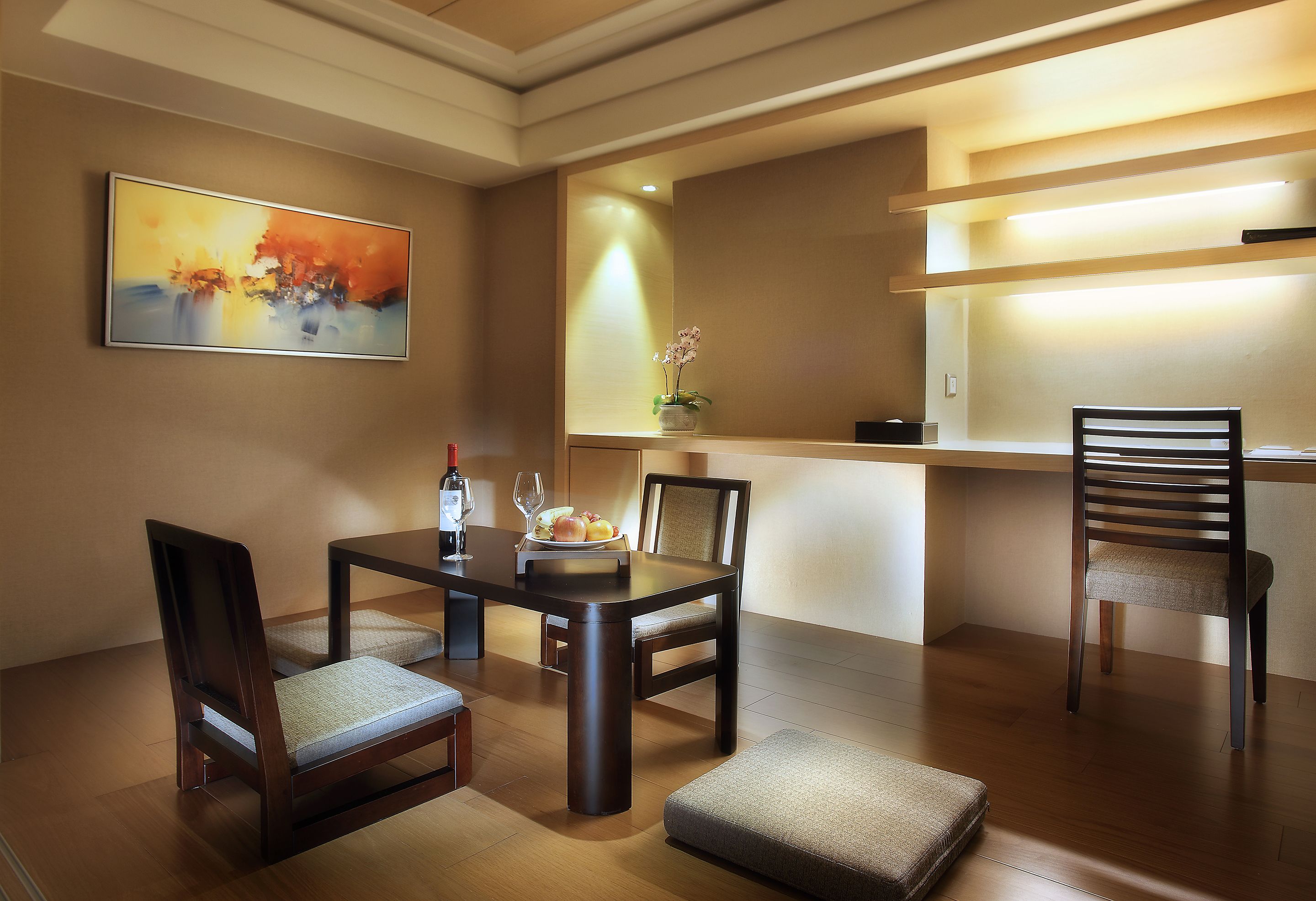 A dining area with a wooden table, two chairs, a bench, a vase with flowers, and a painting on the wall.