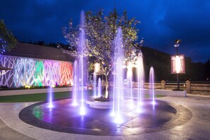 A nighttime fountain with colorful lights, surrounded by a modern building with a geometric facade. - Sun Moon Lake Hotel (Yuchi)