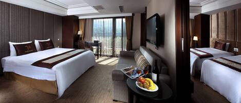 A hotel room with two beds, a TV, a table with fruit and wine, and a balcony with curtains.