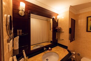 Ein Badezimmer mit Marmorwaschbecken, einem Spiegel, einem Handtuchhalter, einer Glasdusche, einer Toilette und einem an der Wand befestigten Telefon.