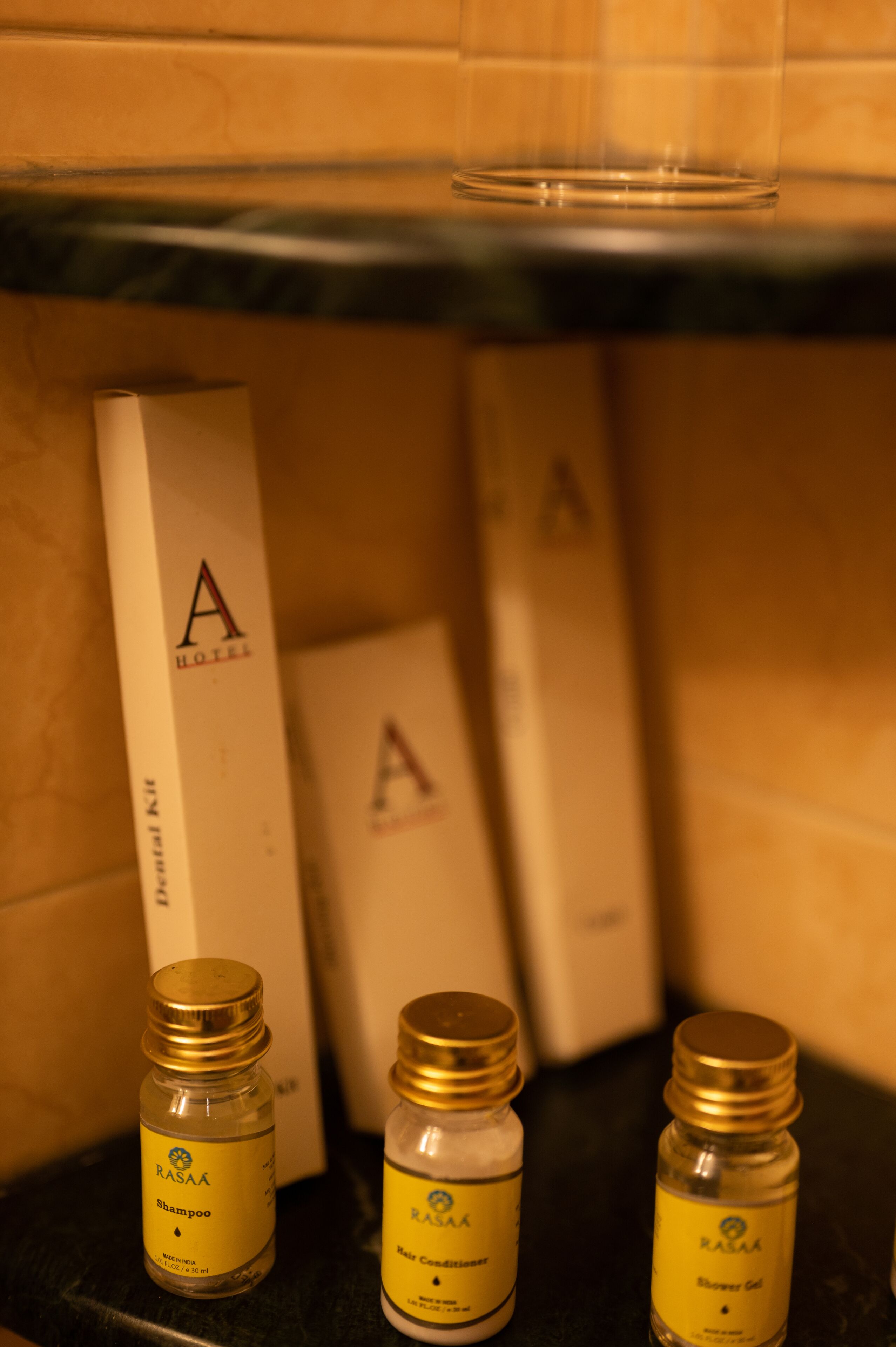 Tres botellas de champú y acondicionador RASA hotel sobre una encimera, con cajas al fondo.