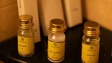 Three bottles of RASA hotel shampoo and conditioner on a counter, with boxes in the background.
