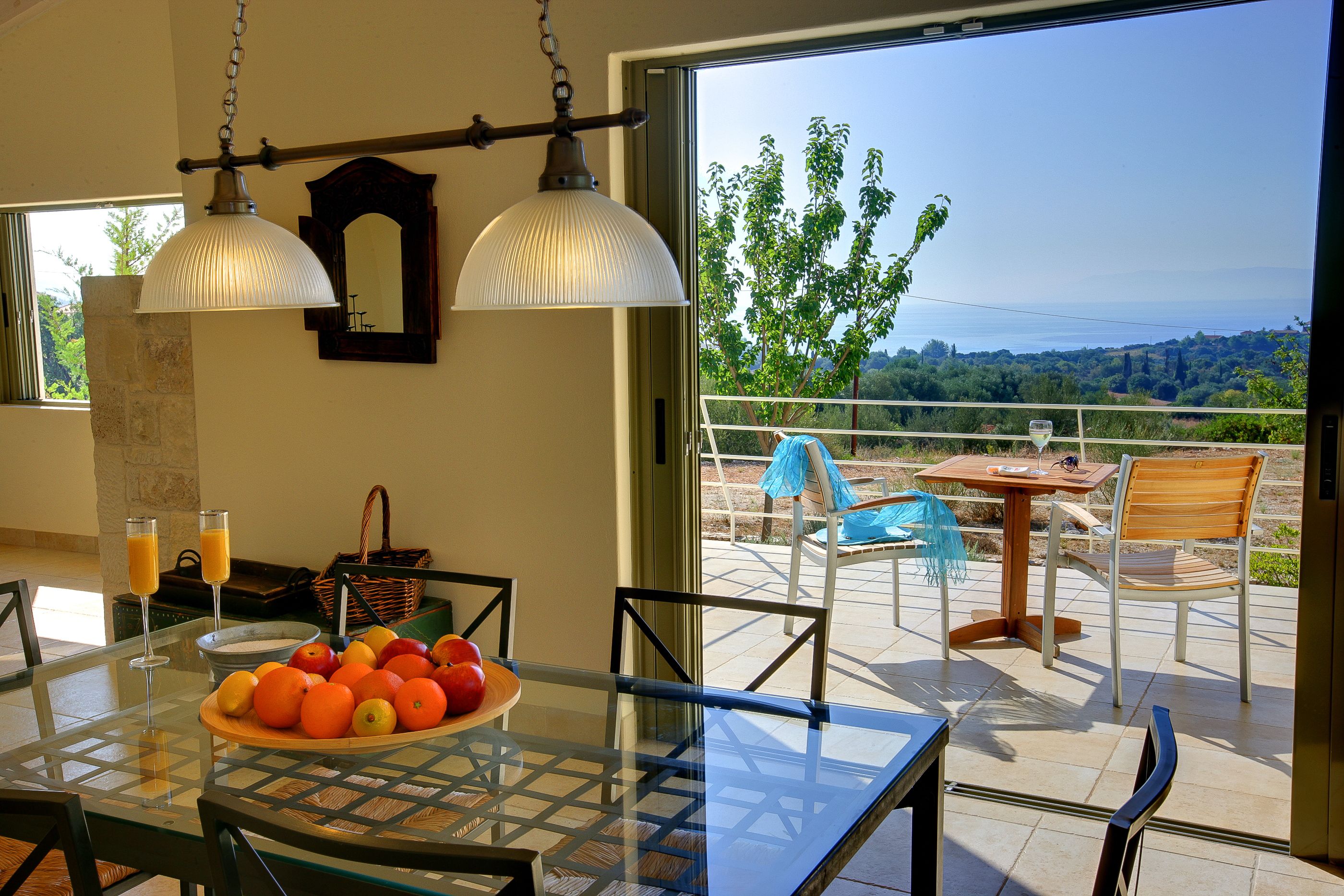 Un comedor con una mesa lista para dos, un frutero y vistas al exterior.