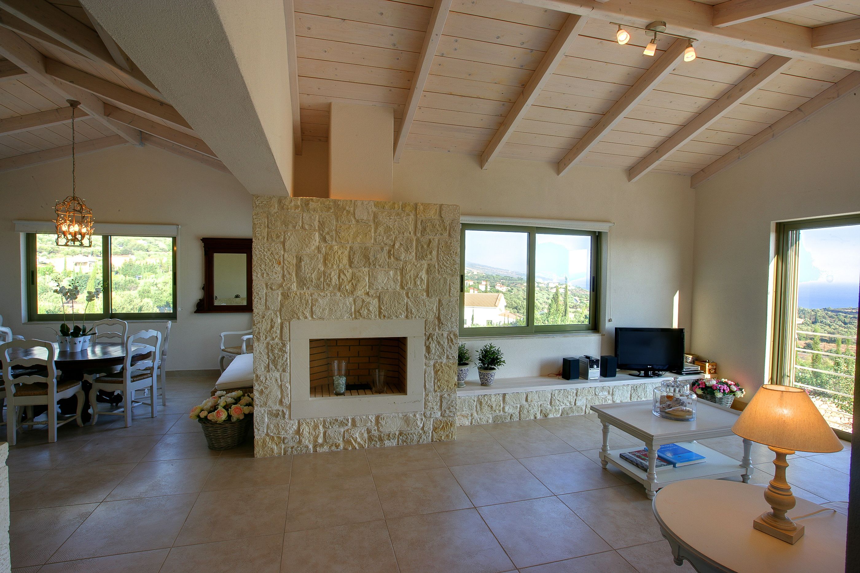 Amplia sala de estar con chimenea de piedra, mesa de comedor, sillas y televisor.