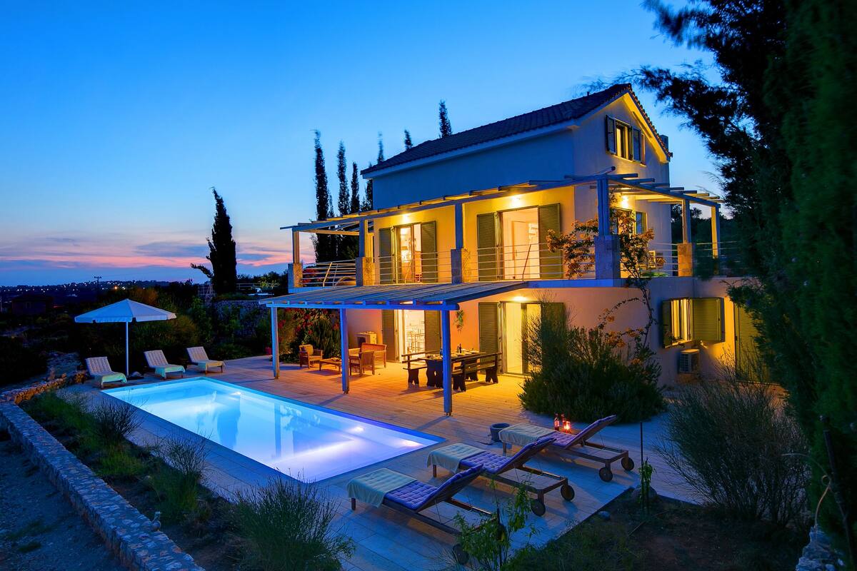 A two-story house with a swimming pool, outdoor seating, and a covered patio area.