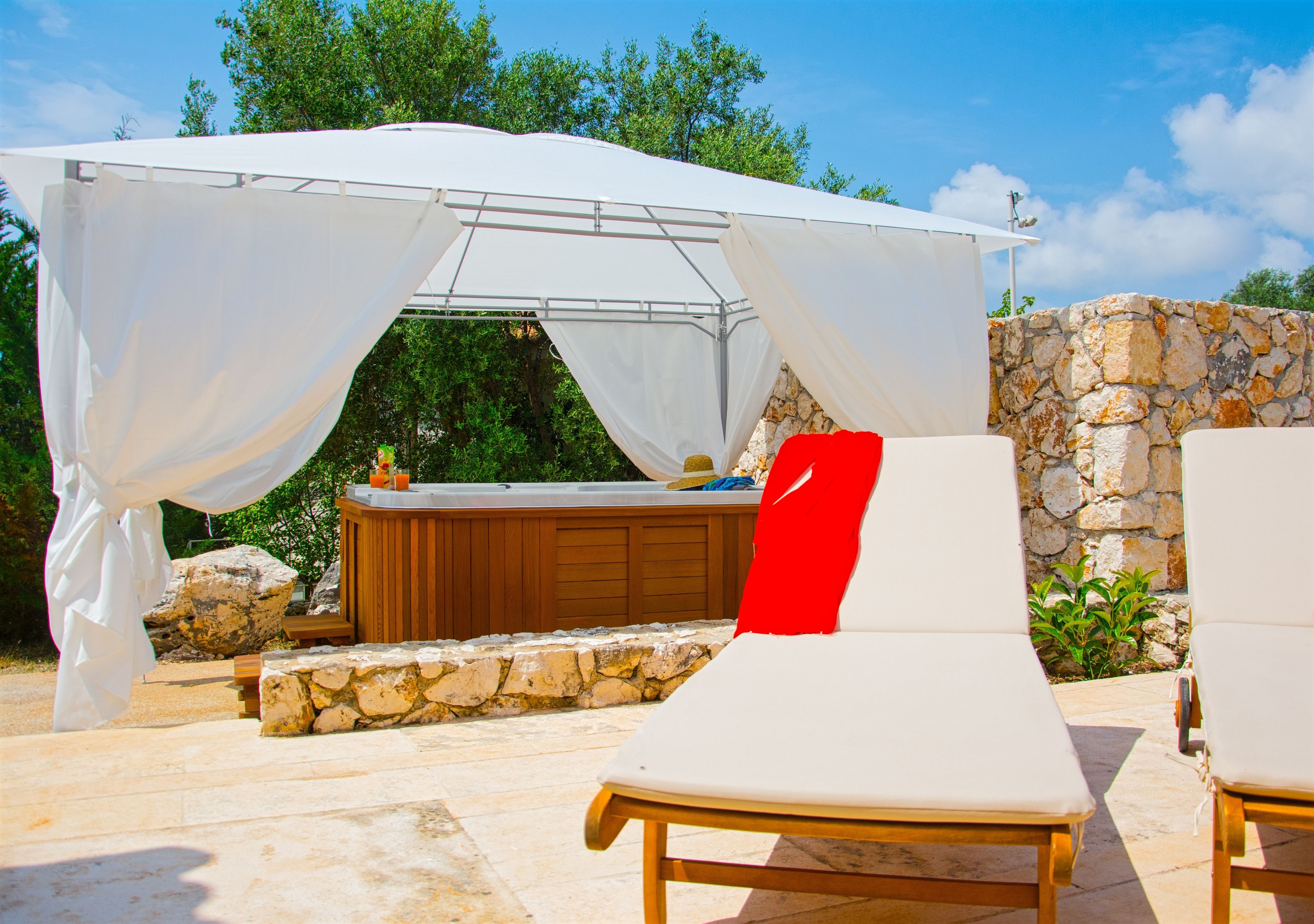 An outdoor seating area with a stone wall and a white canopy.